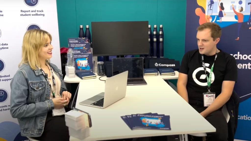 A video screenshot of a man and woman sitting at a desk having an interview